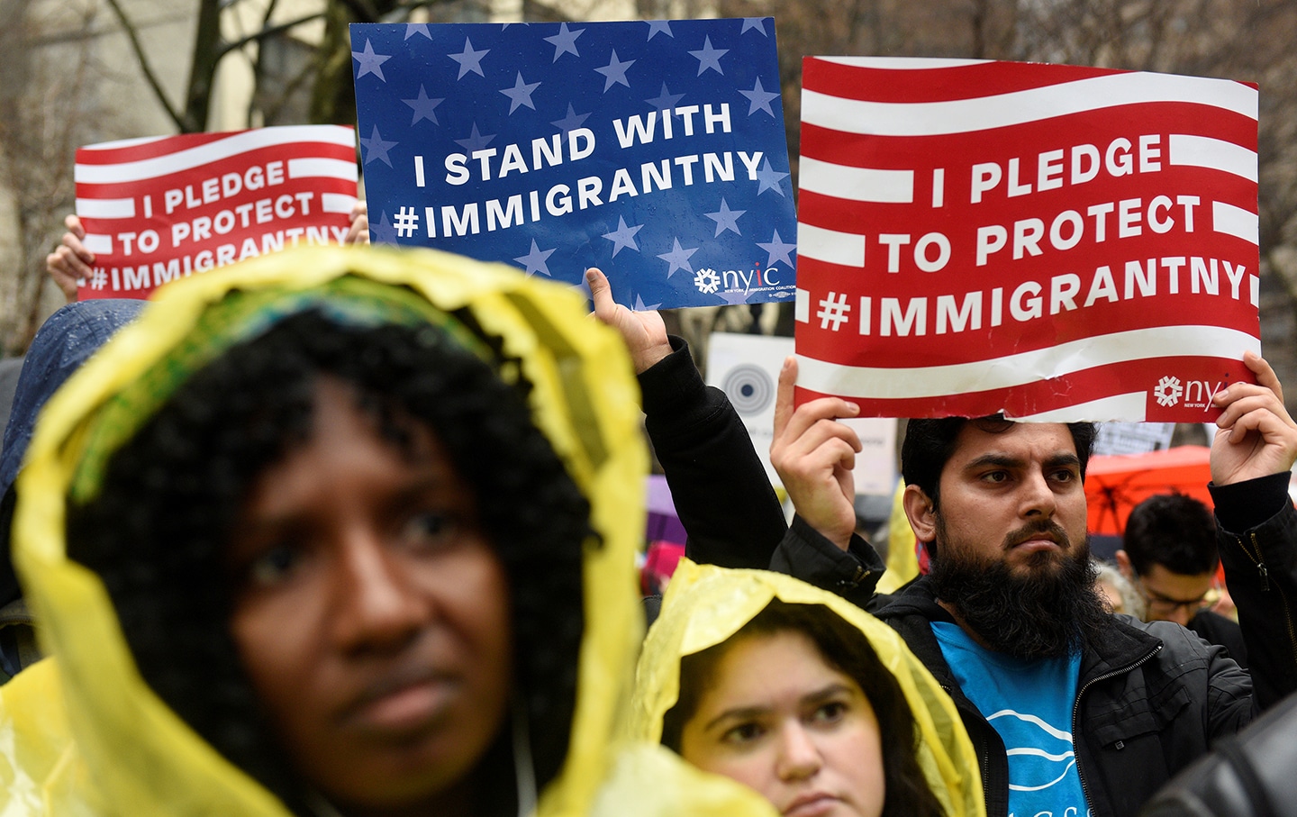 People hold up signs before marching to Trump Tower during a protest against President-elect Donald Trump in Manhattan